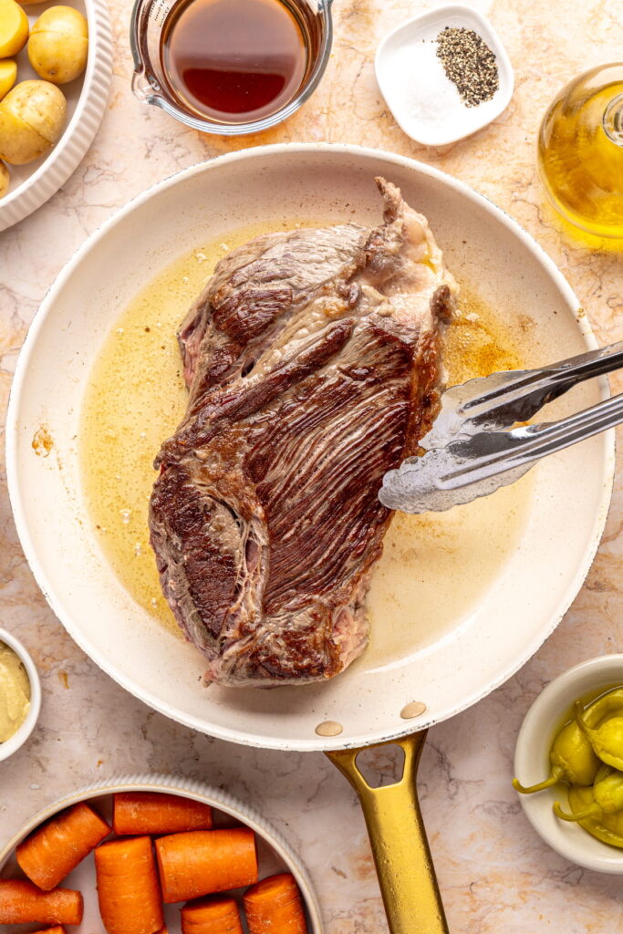 chuck roast searing in a pan