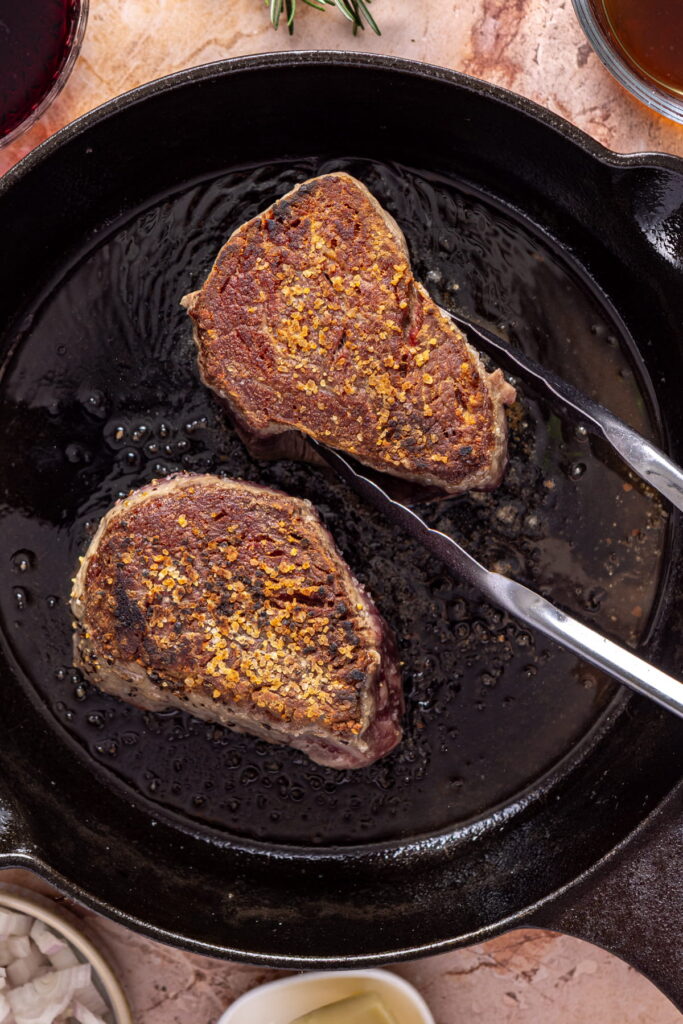 filet mignon being seared in a cast iron pan
