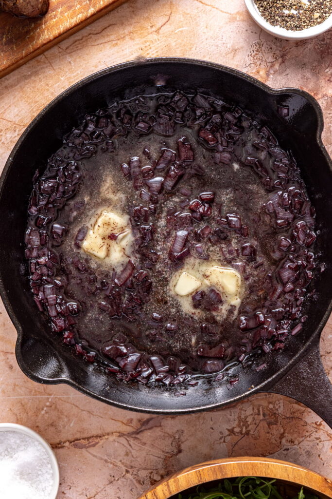 a red wine reduction sauce in a cast iron pan with added butter