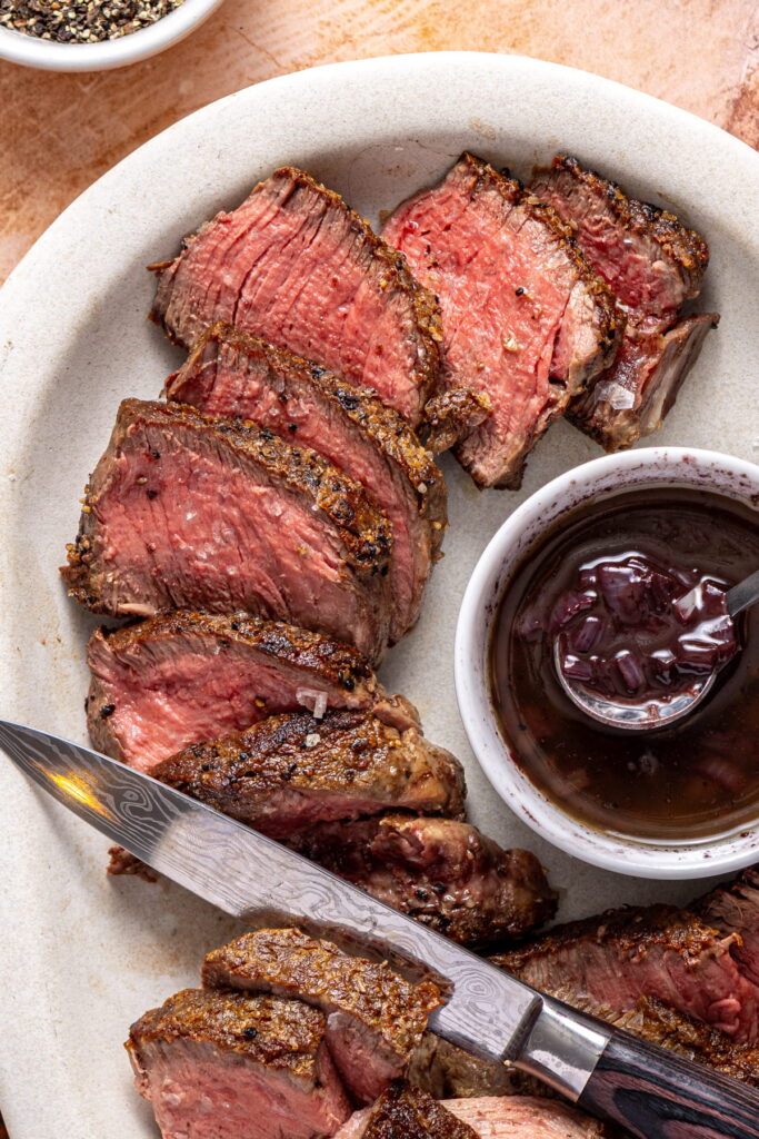 sliced filet mignon with red wine reduction on the side