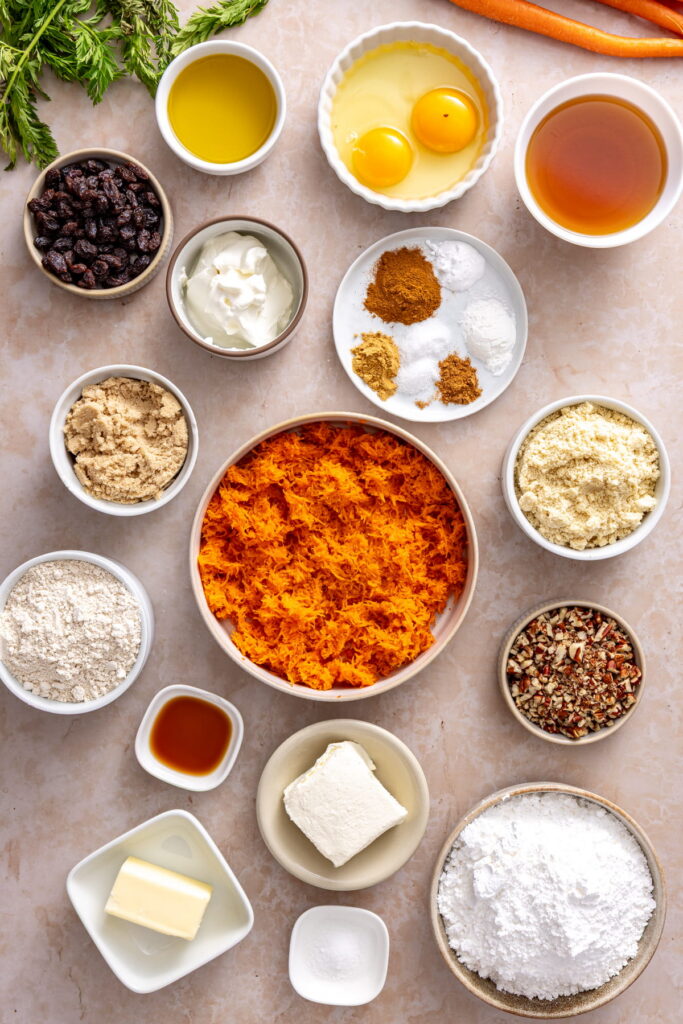 ingredients for gluten free carrot cake arranged in small bowls on a counter