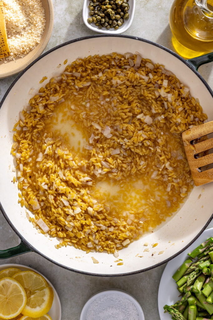 garlic, onion, orzo, and wine in a pan