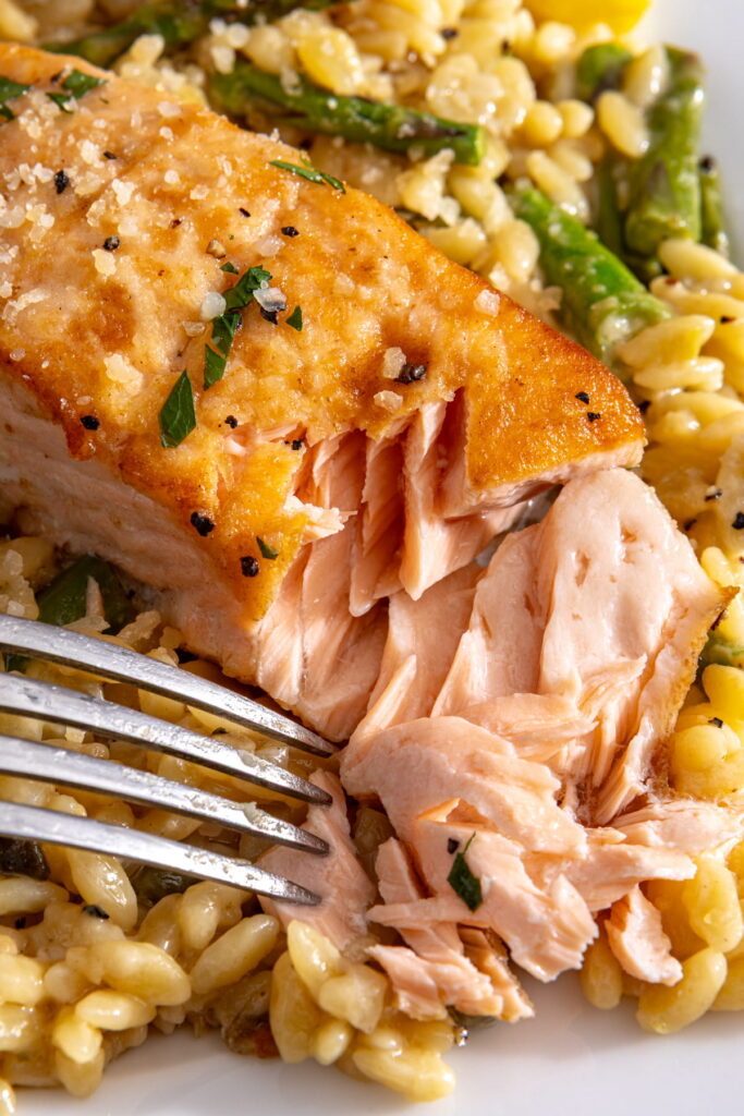 closeup of salmon piccata flaked with a fork
