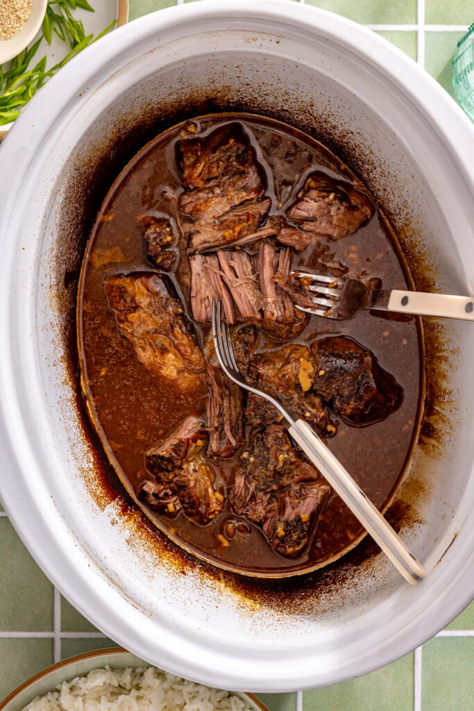 shredded cooked beef in a slow cooker with miso sauce